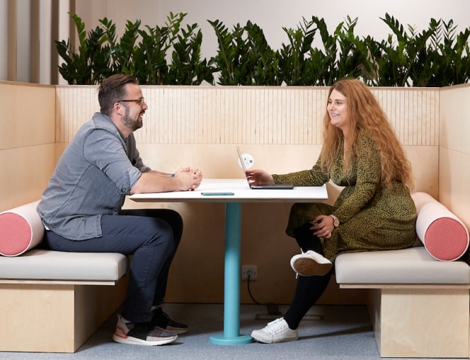 Man and woman meeting at a table in a breakout area